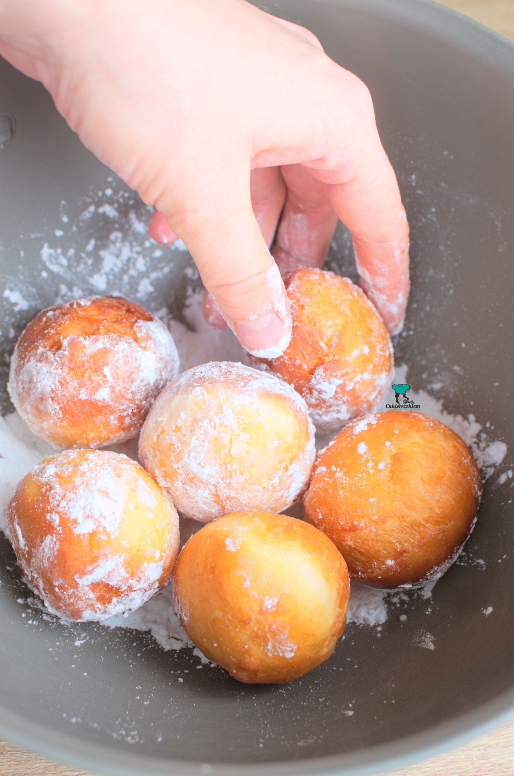 Wystudzone pączki obtaczamy w cukrze pudrze.